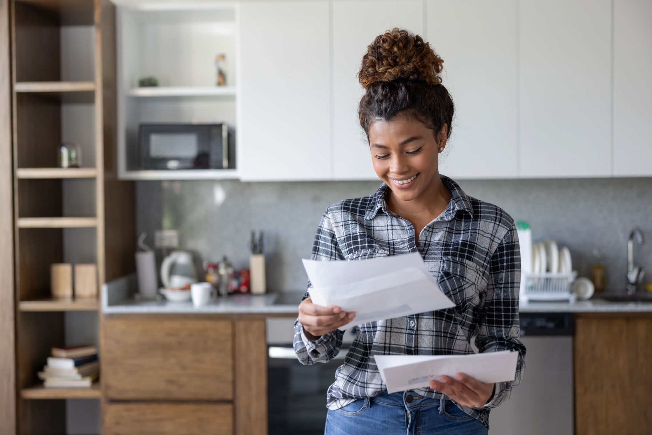 Portrait of a happy Latin American woman at home checking her mail and smiling - lifestyle